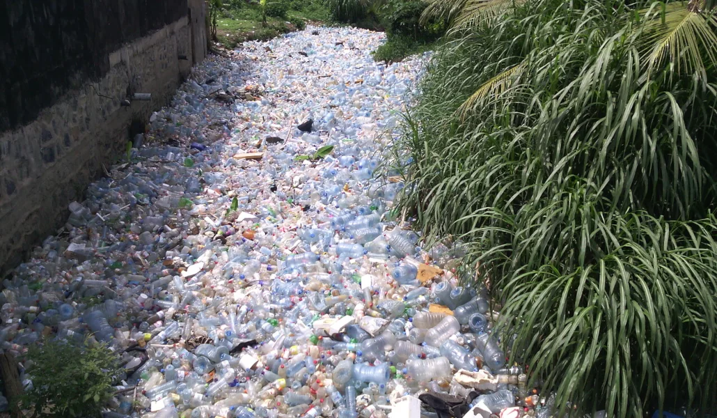 Un cours d’eau complètement recouvert de bouteilles plastiques au quartier Dakar, dans l’arrondissement de Douala 3ème au Cameroun | Photo: Mouenthias / Wikimédia Commons (CC BY-SA 4.0).