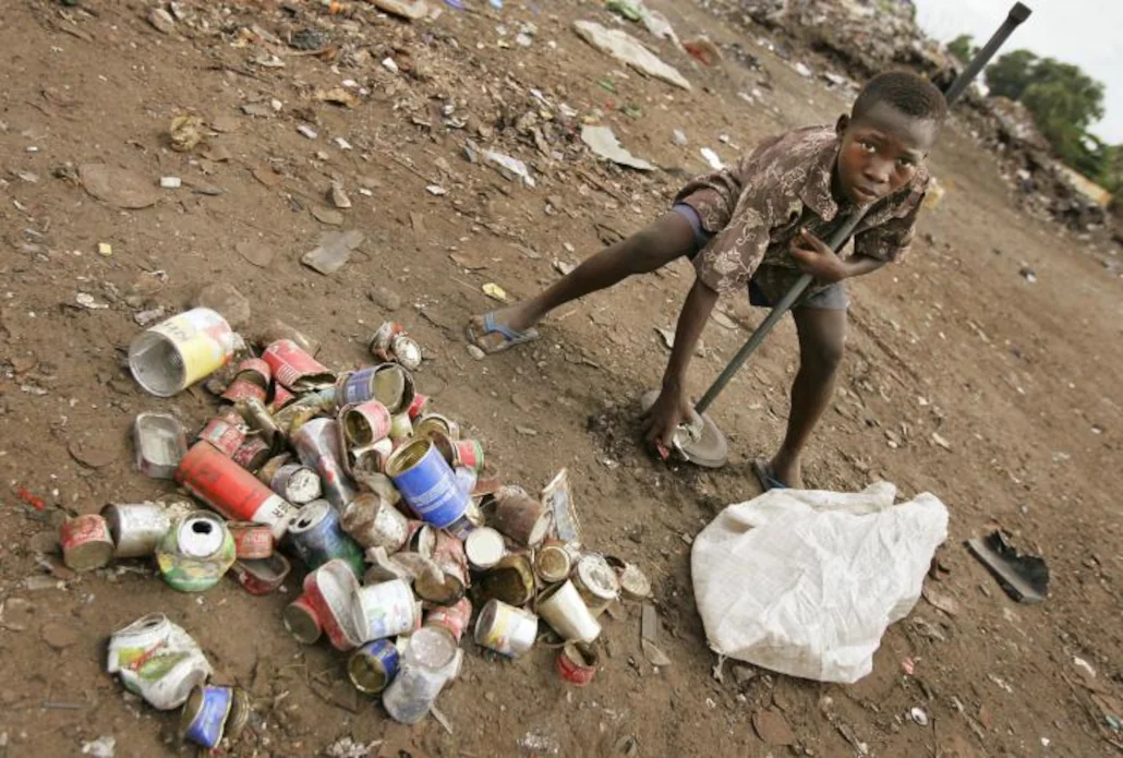 Un jeune garçon ramasse des boîtes de conserve dans une décharge d'un quartier de Lomé, avril 2005 | Photo / Archives: Ben Curtis / AP