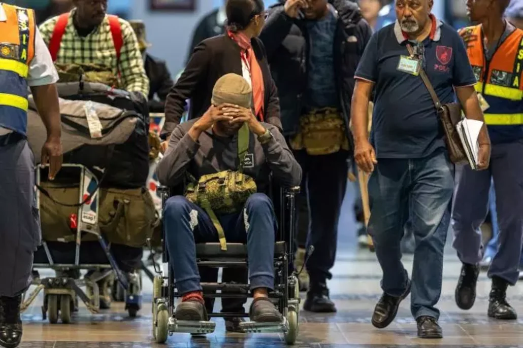Des Sud-Africains qui auraient été victimes d'une ruse pour les pousser à combattre dans la guerre en Ukraine, escortés à leur arrivée à l'aéroport de Durban, en Afrique du Sud, le 25 février. AP/ Str.
