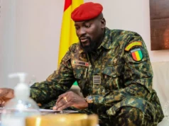 Guinée: Cinq ans de Doumbouya et une « machine répressive affamée » La disparition forcée du magistrat Algassimou Diallo, filmé début septembre dans une prison en Guinée forestière, est un épisode de plus dans la dérive du régime de l’ancien légionnaire français, auteur d’un putsch en 2021. « Algassimou Diallo, détenu à la prison civile de Macenta. » L’homme qui ânonne son nom face caméra, tenue rouge et doigts gigotants, avant de poser droit comme un « I » entre deux lits superposés métalliques, est un magistrat renommé en Guinée. Algassimou Diallo était le procureur du procès du massacre du 28 septembre 2009, très médiatisé. Avant sa déchéance éclair – brutale, serait-on tenté d’écrire –, il avait été affecté à la Cour suprême de Guinée en tant qu’avocat général. Qu’a-t-il fait ? Les accusations portées contre lui, « provocation à la discrimination, à la haine ou à la violence pour discrimination » et « association de malfaiteurs », reposent sur un audio, présenté comme un échange entre le magistrat et l’opposant en exil Cellou Dalein Diallo, prétendument hostile au pouvoir. Malgré les dénégations de ce dernier, qui crie à la fabrication de preuve, Algassimou Diallo a été révoqué illico de ses fonctions par le Conseil supérieur de la magistrature fin août, puis incarcéré à la maison centrale de Coyah, non loin de Conakry. Le 5 septembre, alors que Mamadi Doumbouya se targuait, à l’occasion du 5e anniversaire de son putsch, d’avoir fait du « vivre-ensemble » une « réalité », en référence au recul du « poison » de l’ethnocentrisme, le magistrat était transféré, yeux bandés, dans une prison en Guinée forestière, distante de 700 km. La vidéo du détenu, diffusée au journal de la télévision publique, la RTG, était censée rassurer ses proches, ses collègues et ses avocats, restés sans nouvelles durant plusieurs heures. Plusieurs heures d’inquiétude au cours desquelles ils n’ont pu s’empêcher d’envisager une énième disparition forcée perpétrée par le régime. Des dizaines d’individus en ont été victimes depuis que Mamadi Doumbouya est aux affaires. L’organisation Tournons la page Guinée (TLP-Guinée) a pu documenter trente-cinq cas, et a lancé le 6 août la plateforme memoireguinee.org, en vue de collecter et de vérifier de nouveaux témoignages. La peur du kidnapping par les commandos du pouvoir a été ravivée de façon tragique dans le pays le 24 août. Un charnier contenant six corps, yeux bandés et mains ligotées, a été découvert par des villageois, près de la préfecture de Forecariah. Et à moins de 10 kilomètres d’un camp des forces spéciales, le corps de Mamadi Doumbouya. Kouma Média, composé de journalistes guinéens en exil, avait révélé en mai que le camp abritait un lieu de détention et de torture illégal, réservé aux « enlevés ». Les corps exhumés de ce charnier auraient pu faire l’objet d’« exécutions extrajudiciaires, sommaires ou arbitraires », ont alerté, quant à elles, le 30 août, une vingtaine d’organisations de la société civile africaines. Les autorités ont annoncé une enquête. Mais aucun résultat d’autopsie n’a été rendu public, pas plus que l’identité des individus gisant sous terre. « Qu’il s’agisse de l’incendie du dépôt de carburant de Conakry en décembre 2023, de l’usage excessif de la force dans un stade qui a causé la mort de plus de 140 personnes à N’Zérékoré en décembre 2024, des disparitions forcées, on n’a jamais vu de bilan, de rapport public et encore moins de mesures prises pour que les auteurs répondent de leurs responsabilités », déplore Abdoul Sacko, coordinateur du Forum des forces spéciales de Guinée (FFSG), l’un des très rares « relâchés » après avoir été enlevés puis torturés. Il est actuellement en exil. Ces événements jalonnent le contre-récit des cinq années de pouvoir de Mamadi Doumbouya. Un « mandat » au cours duquel les droits et libertés sont décidément étouffés, méprisés, enterrés, sur fond de musellement de la presse et de dissolution des partis politiques. Concomitamment à l’arrestation d’Algassimou Diallo et à la découverte de cette fosse commune, un autre drame a secoué la Guinée. Dans la nuit du 22 au 23 août, la décharge publique de Dar es-Salam, à deux pas de l’aéroport international de Conakry, s’est effondrée, causant la mort de trente-six personnes. L’événement est survenu le jour de la fermeture programmée du site, dans la cadre d’un projet financé à hauteur de 70 millions d’euros par l’Union européenne et l’Agence française de développement, et prévoyant notamment la construction d’un Centre d’enfouissement moderne, relève le FFSG dans un communiqué. Pourtant, la veille au soir, un bulldozer juché au sommet de la montagne de déchets s’activait encore pour tasser de nouvelles ordures. Ce projet aurait été ralenti et négligé par les autorités, peut-être parce qu’il n’était pas assez rentable à court terme, avance Abdoul Sacko. « Pire, » poursuit-il, le chef de l’État s’est rendu sur les lieux du drame sans aller au chevet des familles de victimes, des blessés, ou des sans-abris. Des opérations de déguerpissement sans processus de relocalisation ont été rapidement conduites dans la foulée. Comme si on ajoutait de la douleur à la douleur, sans tenir compte, à aucun moment, de la vulnérabilité des populations ». Dans son post du 5 septembre sur sa page Facebook, Mamadi Doumbouya n’a rendu hommage qu’aux militaires tombés lors du coup d’État du 5 septembre 2021, en refusant que « la République de Guinée continue de s’abîmer ». Il a par ailleurs, comme à son habitude, évoqué les promesses de Simandou, en référence à l’un des plus grands gisements de fer du monde, dont le minerai est exploité et exporté depuis le mois de janvier. Simandou 2040, censé transformer la richesse minérale en manne pour le développement économique de la Guinée, demeure à ce jour nimbé d’opacité. Aucun programme n’a été publié. La brutalité de la gouvernance de l’ancien légionnaire français, en revanche, est bien concrète. Selon Abdoul Sacko, le cas Algassimou Diallo témoigne d’un énième serrage de vis et envoie le message suivant : « plus personne n’est à l’abri ». « Quand elle aura fini de neutraliser tous les contre-pouvoirs, la machine répressive se tournera vers d’autres acteurs. C’est une machine qui ne peut pas rester sans nourriture, elle est affamée ». TLP-Guinée, de son côté, a dénoncé le 7 septembre dans un communiqué l’irrégularité de la procédure de transfert d’Algassimou Diallo. Et d’alerter : « Tant qu’il n’aura pas été présenté à son juge, à Conakry, en présence de ses avocats et familles, nous considérerons que sa vie est en danger. » A.F. Source: AfriqueXXI.info